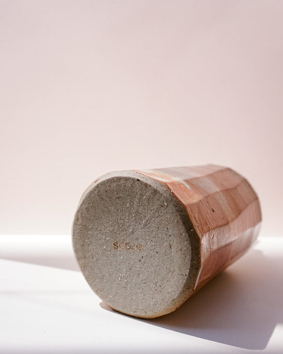 A handmade ceramic vase with a hexagonal body, shown lying on its round base. The base is a textured gray concrete-like finish with a small stamped 'SCREE'. Oil Bottle | Scree Ceramics | Fodder