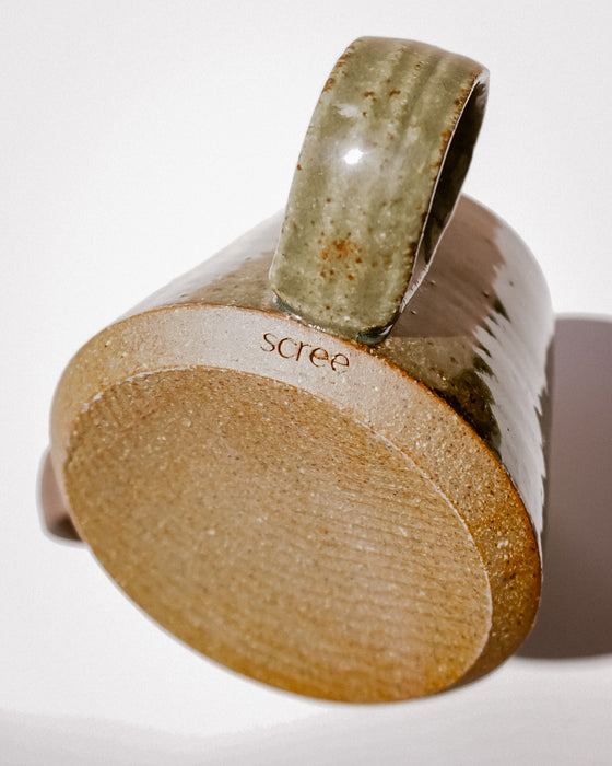A close-up studio shot of a ceramic mug showing its thick handle, textured glazed surface, and the brand name 'scree' printed on the side, set against a clean white background. Tall Loop Mug | Scree Ceramics | Fodder