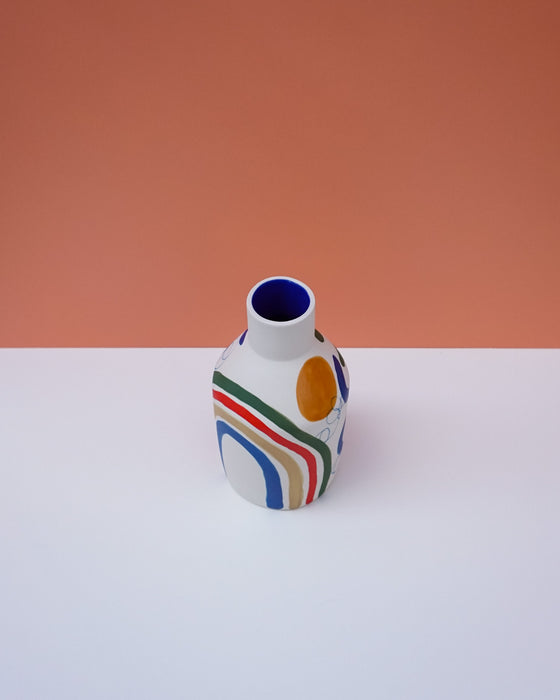 Ceramic vase with colorful abstract design on a white surface and peach background. Sophie Alda | Handmade Ceramics | Shop Fodder