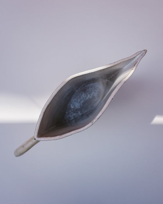 Metallic leaf-shaped object on a reflective surface. Sophie Alda | Handmade Ceramics | Shop Fodder