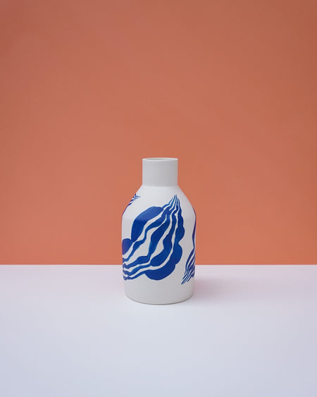 White bottle with blue wave design on a peach background. Sophie Alda | Handmade Ceramics | Shop Fodder