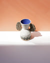 Ceramic vase with blue interior and textured surface on a peach and white background. Sophie Alda | Handmade Ceramics | Shop Fodder