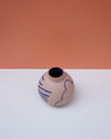 Ceramic vase with blue abstract patterns on a white surface with a peach-colored background. Sophie Alda | Handmade Ceramics | Shop Fodder