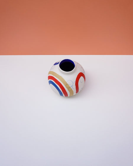 Small ceramic vase with colorful design on a white surface with a peach background. Sophie Alda | Handmade Ceramics | Shop Fodder