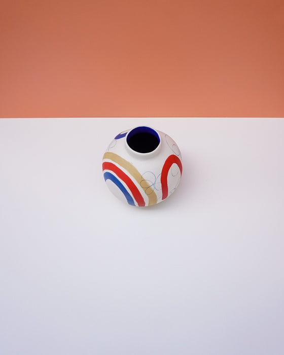 Small ceramic vase with colorful design on a white surface with a peach background. Sophie Alda | Handmade Ceramics | Shop Fodder