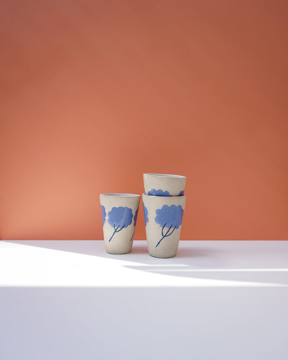 Three ceramic cups with blue floral designs on a peach background. Sophie Alda | Handmade Ceramics | Shop Fodder