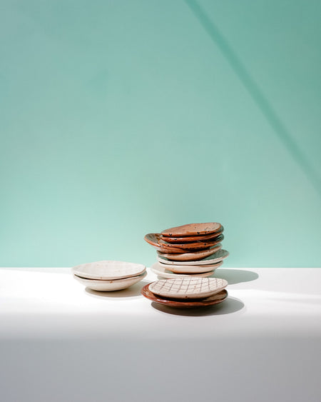 Stack of ceramic plates on a light surface with a light blue background. Diddy Bowl | Jode Pankhurst | Shop Fodder