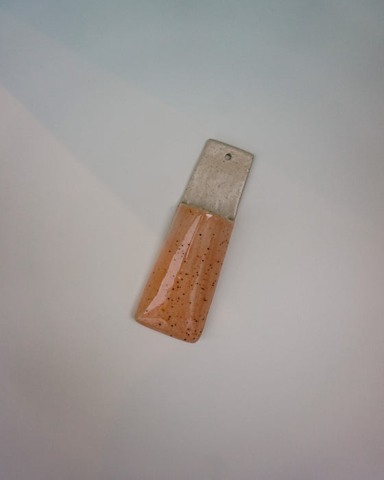 Rectangular object with speckled brown top and metallic bottom on a light gray background | Jode Pankhurst