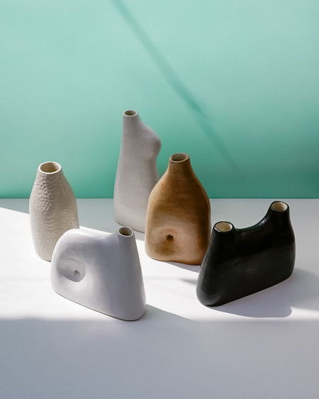 Five ceramic vases in different colors on a light surface with a teal background | Jode Pankhurst