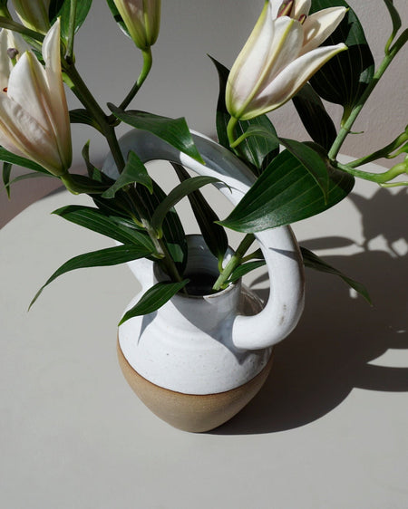 Lily Pearmain Ceramics | Doughnut Vase | Shop Fodder. A bellied vase with an oversized round handle at the top. with a bunch of lillies. 
