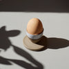 a stoneware egg cup, half glazed in white in the sunshine with an egg in it | Lily Pearmain | Shop Fodder