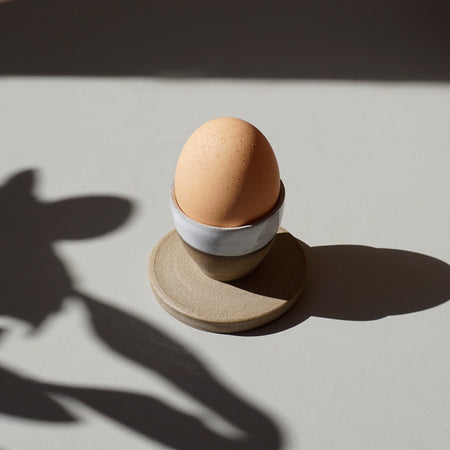 a stoneware egg cup, half glazed in white in the sunshine with an egg in it | Lily Pearmain | Shop Fodder