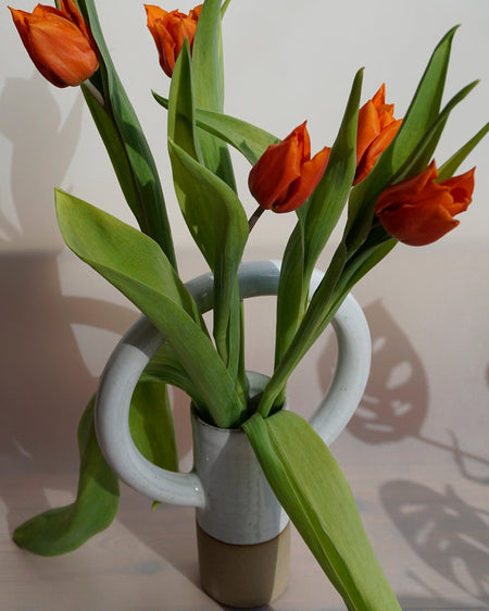 Lily Pearmain Ceramics | Doughnut Vase | Shop Fodder. A straight vase with an oversized round handle at the top. and a bunch or red tulips