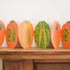 Decorative paper pumpkins on a wooden surface against a white wall. Pumpkin Handprinted Garland | East End Press | Shop Fodder