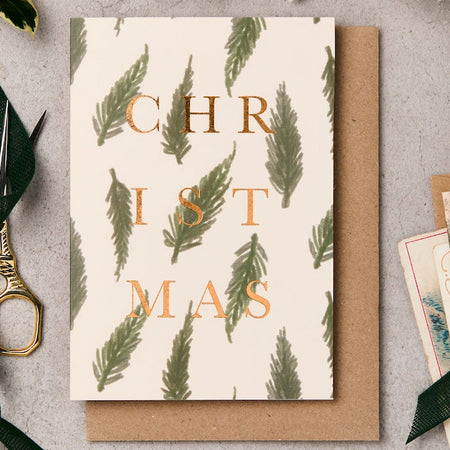 Christmas card with green leaf pattern and scissors on a gray surface