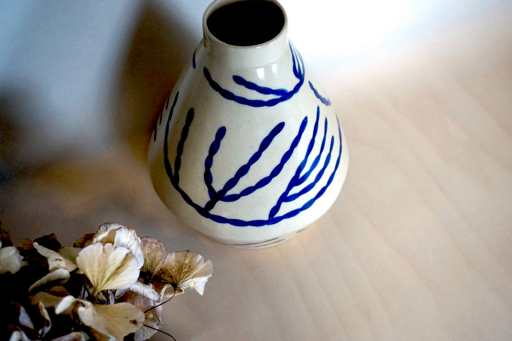 dried hydrangeas next to a porcelain vase with a hand painted blue pattern.  