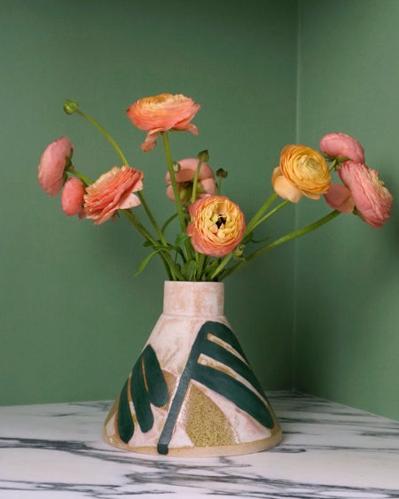 cone shaped vase with a leaf pattern and pinky yellow flowers on a marble table with a green background. Sophie Alda | Handmade Ceramics | Shop Fodder