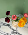 Vase with pink, red, and yellow flowers on a marble surface against a green wall. Sophie Alda | Handmade Ceramics | Shop Fodder