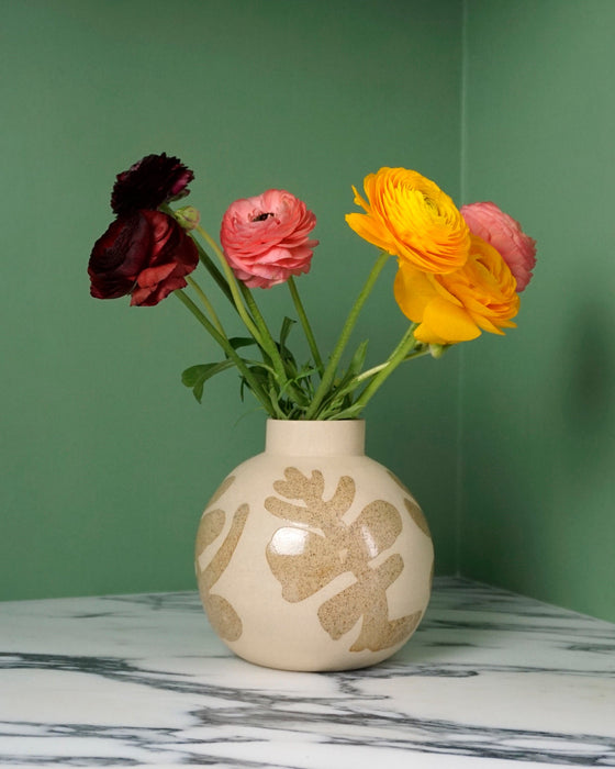 Decorative vase with floral arrangement on a marble surface against a green wall. Sophie Alda | Handmade Ceramics | Shop Fodder