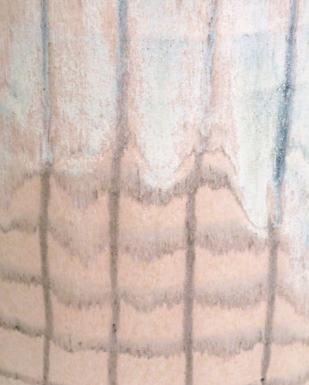 handmade jug with a crosshatch pattern and yellow handle on a marble table with a green background. 