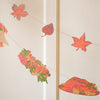 Decorative string with autumn-themed items including leaves and flowers on a light background. Thanksgiving Handprinted Garland | East End Press | Shop Fodder