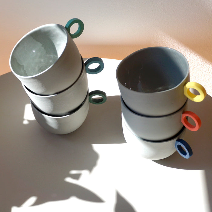 6 round grey cups in two stacks of three. all with different colour handles. Syros Mug | Anna Jones Ceramics | Shop Fodder