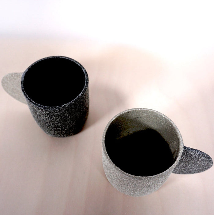 two espresso cups in different shades of grey on a light background. 