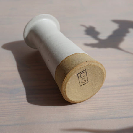 white and stoneware candlestick holder lying on its side so you can see the makers mark of Cara Guthrie on the bottom. 