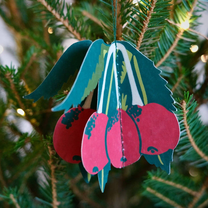 Decorative pink and green ornament hanging on a Christmas tree. East End Press | Shop Fodder