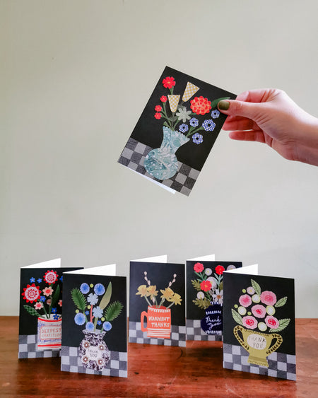 Hand holding a floral card with other cards on a wooden surface and light gray background. Make your own thank you cards | Hadley Paper Goods | Fodder